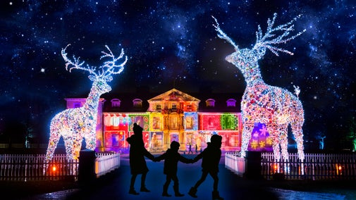 A family are seen in front of the illuminated house at Dunham Massey at Christmas